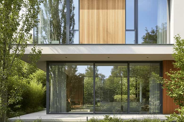 Modern home with slim aluminium-framed windows and doors opening to a lush garden