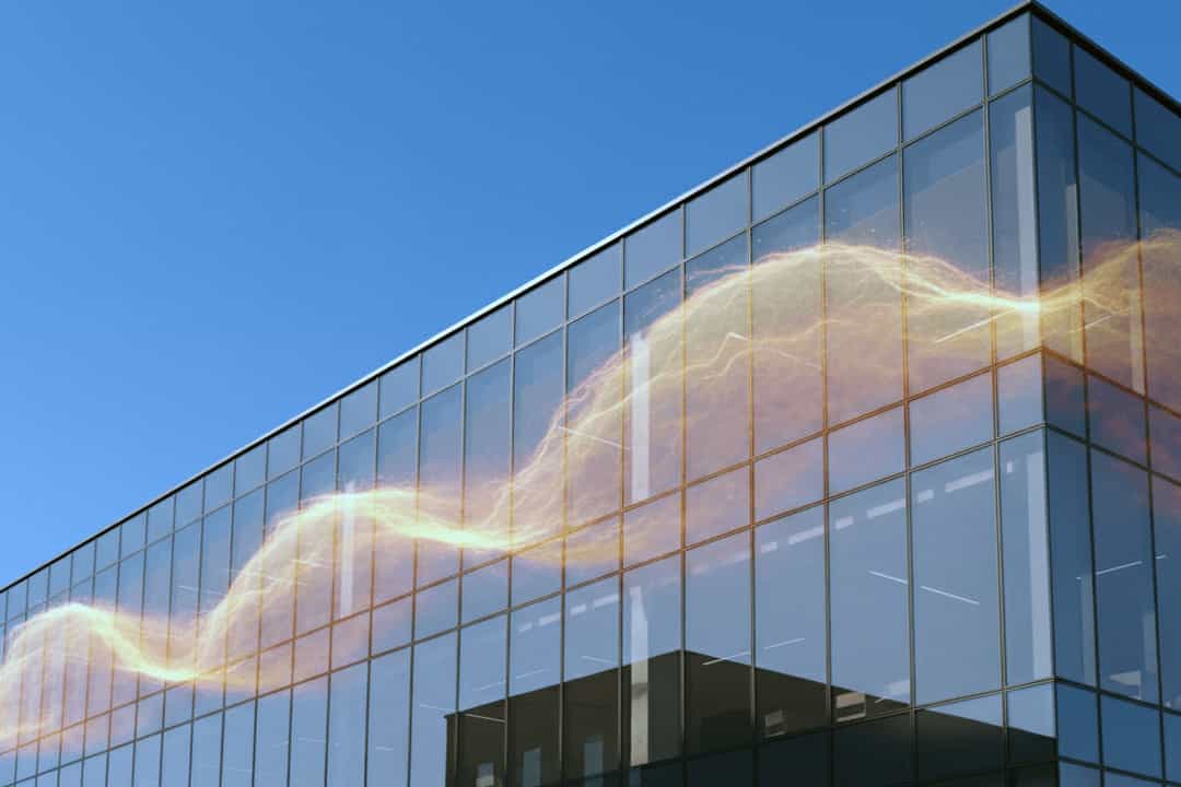 Modern building with solar control glass windows visibly repelling the sun's heat on a bright day.