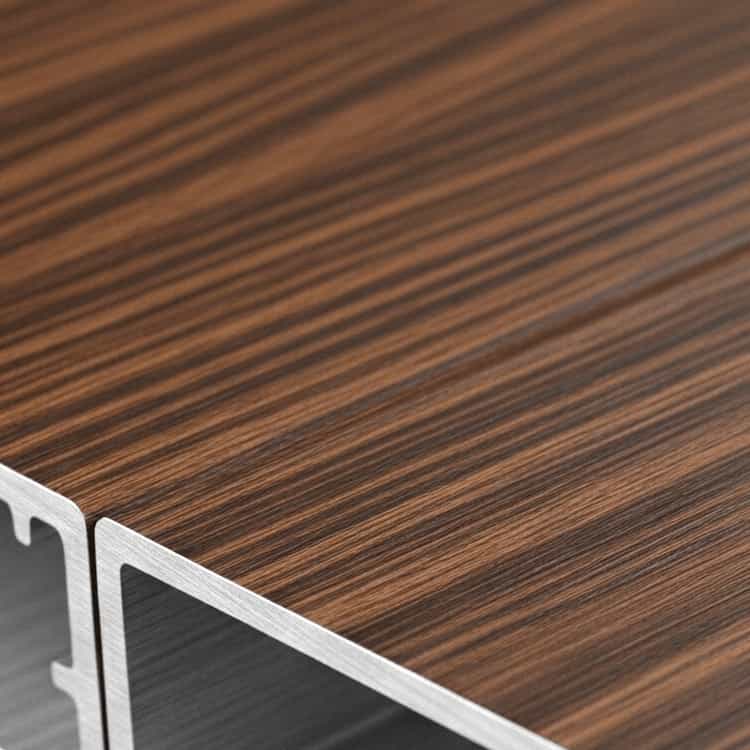 Close-up view of two wood-effect aluminium profiles showing detailed wood grain texture.