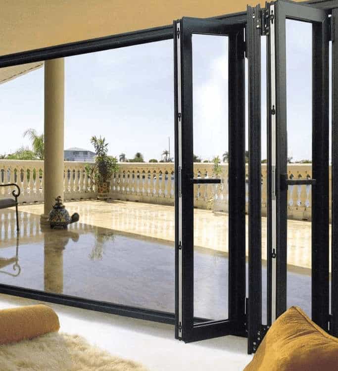 Black-frame bi-fold folding doors opening to a bright balcony area with outdoor views.
