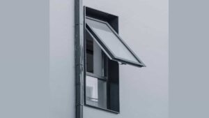 A grey aluminium awning window opened outward for ventilation during light rain in a modern residential bathroom.