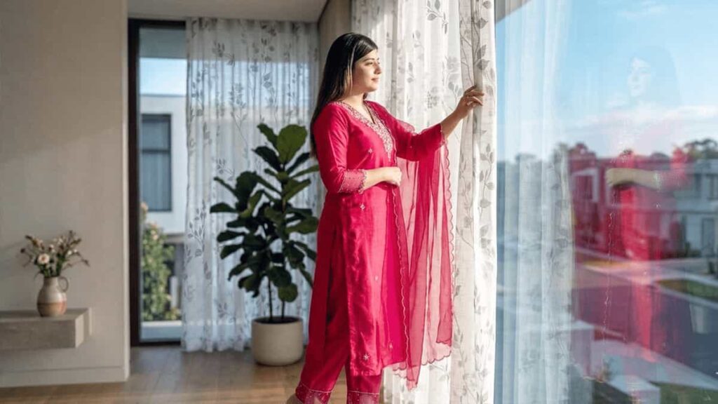 Woman standing near glass window with sunlight showing energy efficiency through SHGC and U-Value